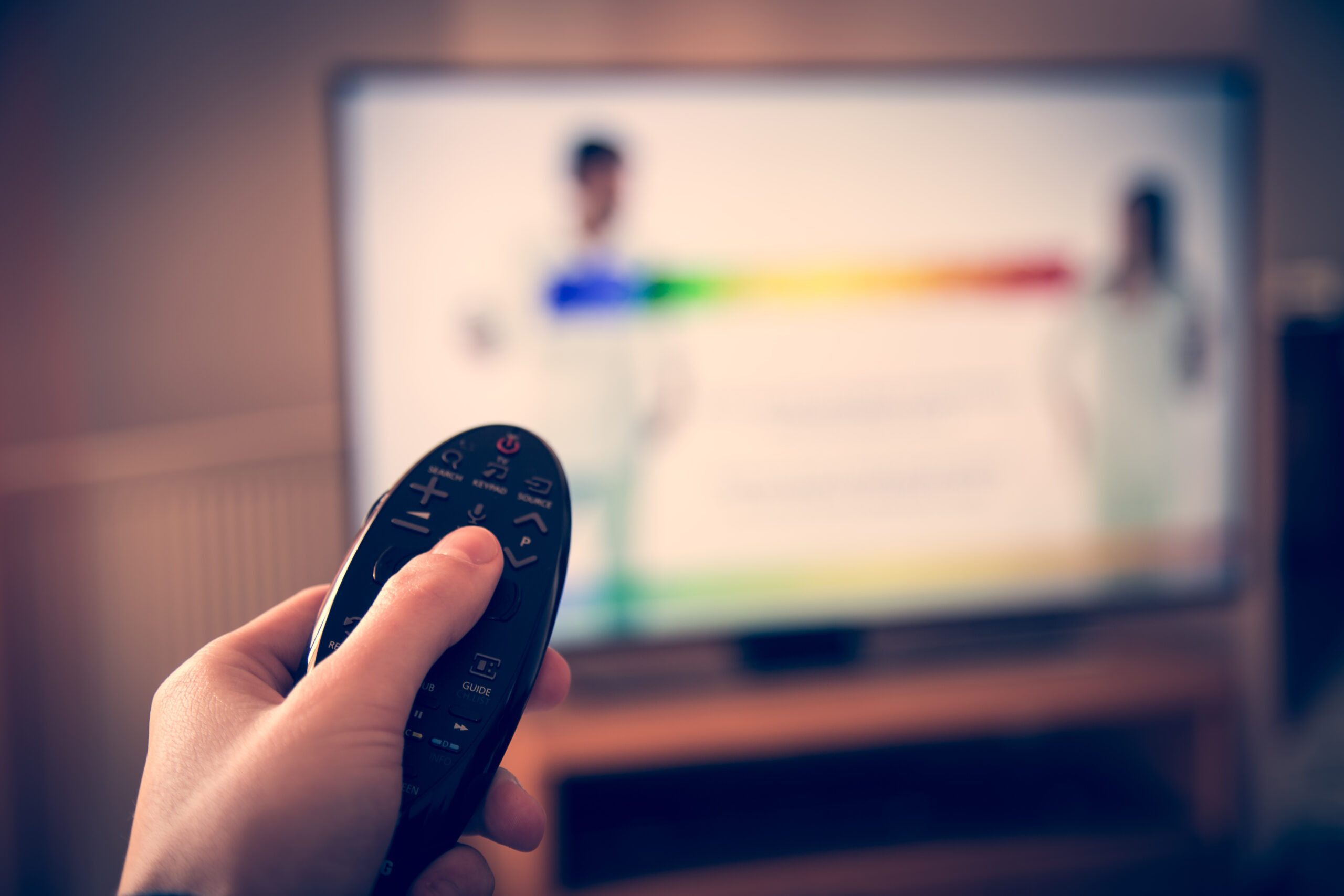 person with remote control watching smart TV
