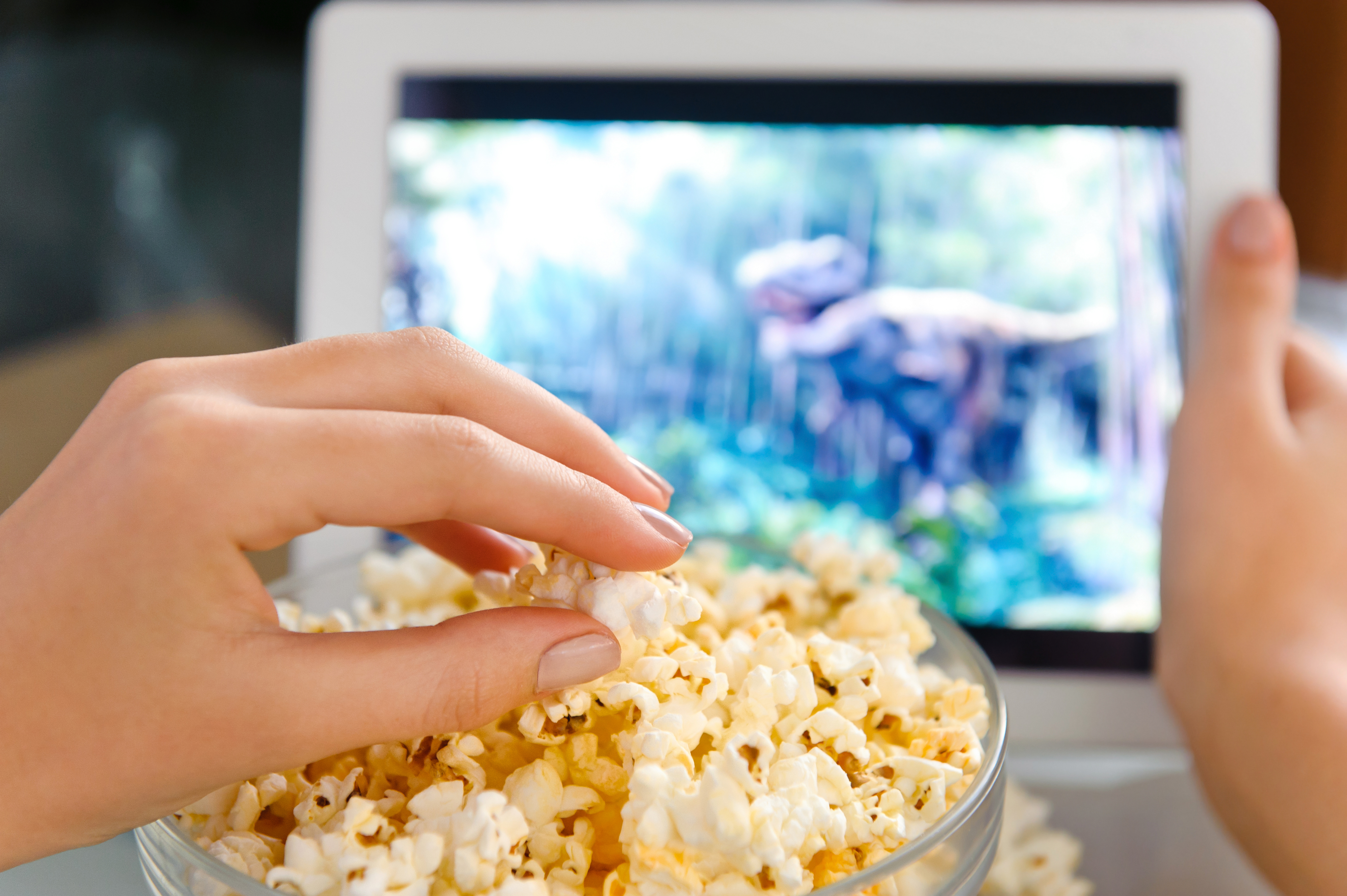 Woman with a bowl of popcorn watching a film on a tablet