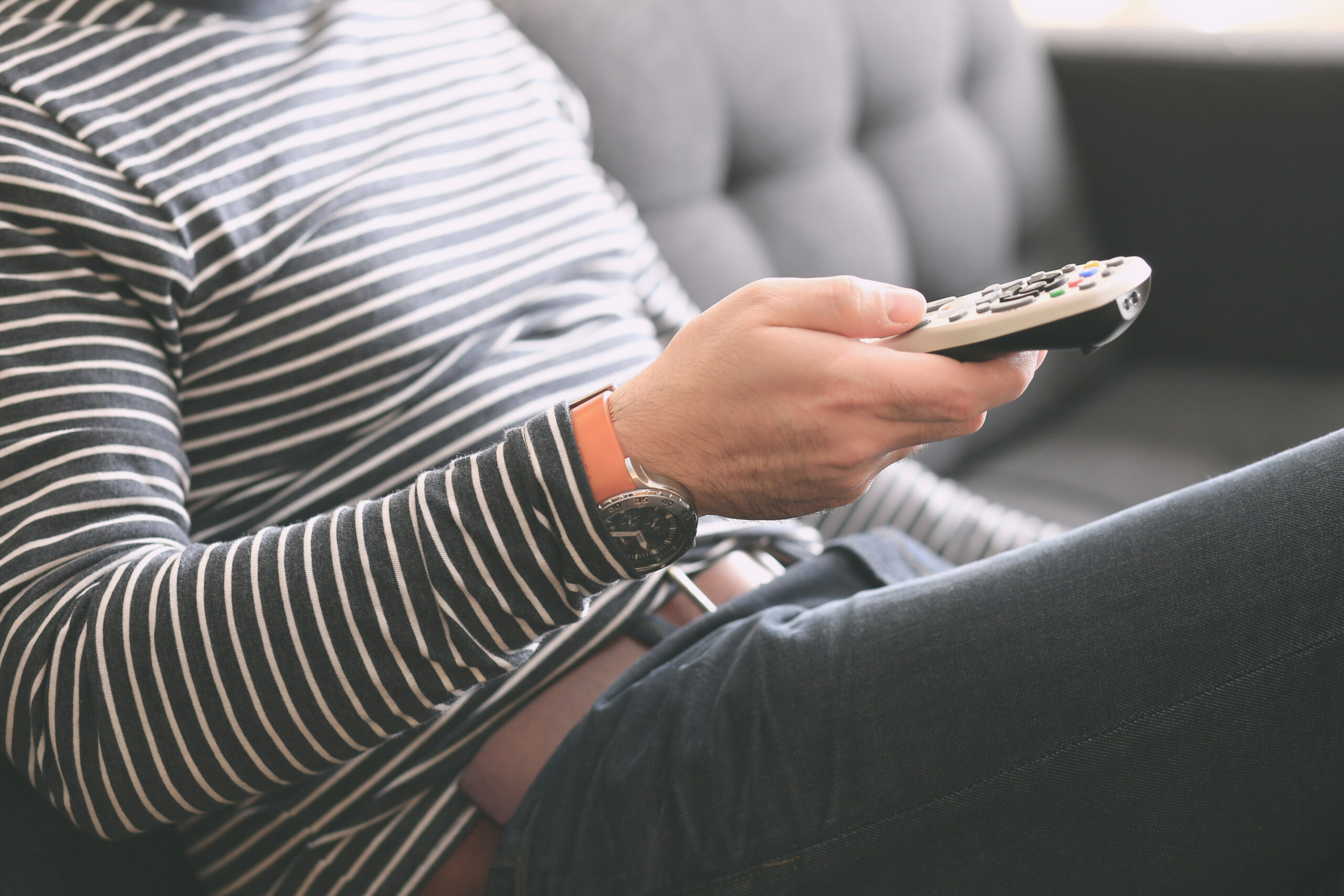 Man turning on TV with remote control