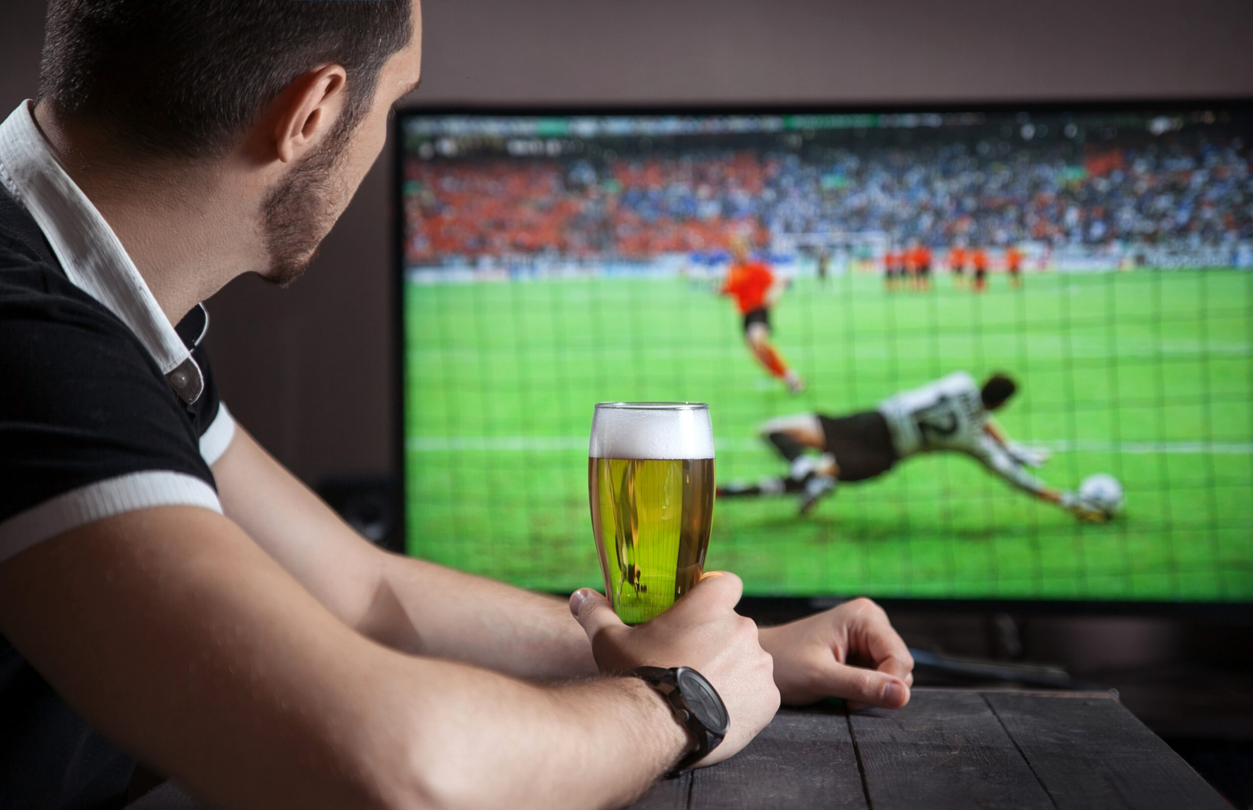 Man with a pint of beer watching the football on TV in a pub